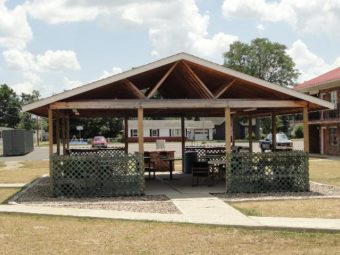 BBQ Pavillion with roof, grills, tables, chairs, trash bins, gravel sourround, walkways and grassy area